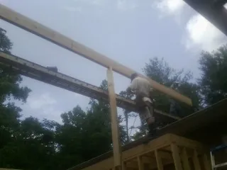 Carpenter setting a ridge beam over a new addition frame — Ice Dam Removal by Roofing Brothers in Lanett