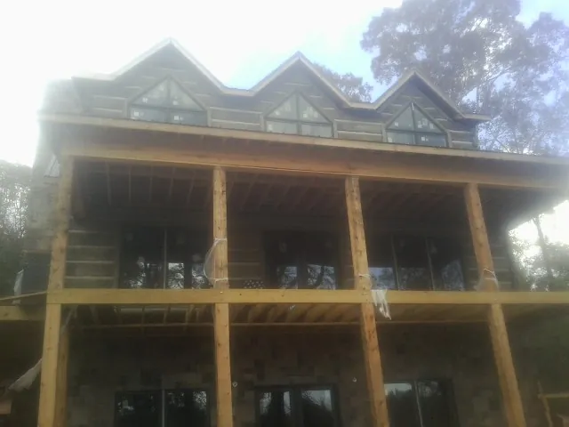 Dormers and porch framing on a large log home under construction — Roof Coating work by our crew in Lanett