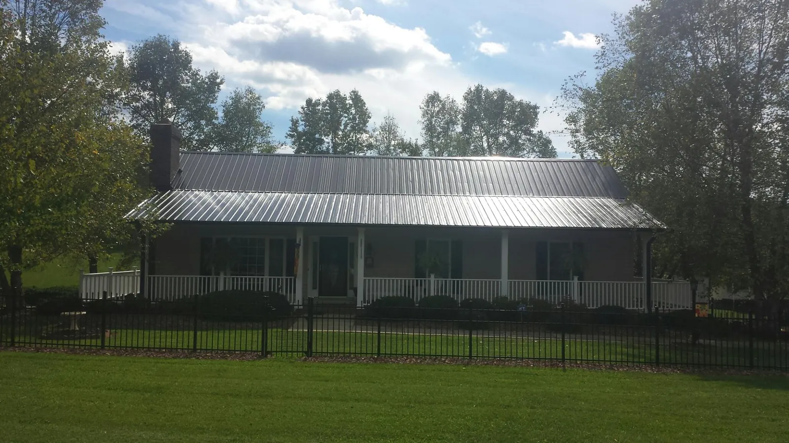 Gray metal roof on a brick ranch with a full width front porch — Gutter Guard Installation work by our crew in Lanett