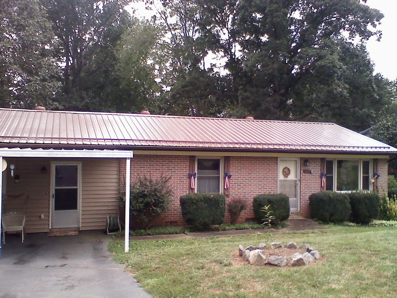 Bronze metal roof and carport on a brick ranch home — Roof Repair work by our crew in Lanett
